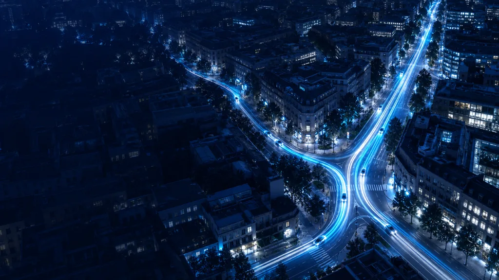 Aerial night view of a city where cyan taxi light trails merge into one shared route